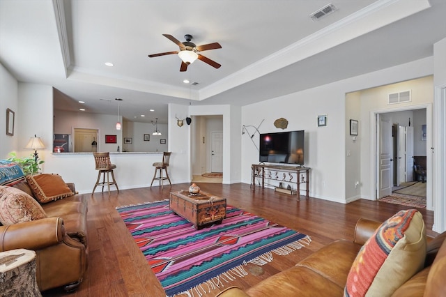 living area featuring a raised ceiling, wood finished floors, and visible vents