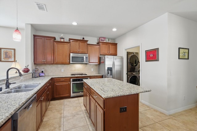 kitchen with visible vents, decorative backsplash, stacked washer and clothes dryer, stainless steel appliances, and a sink