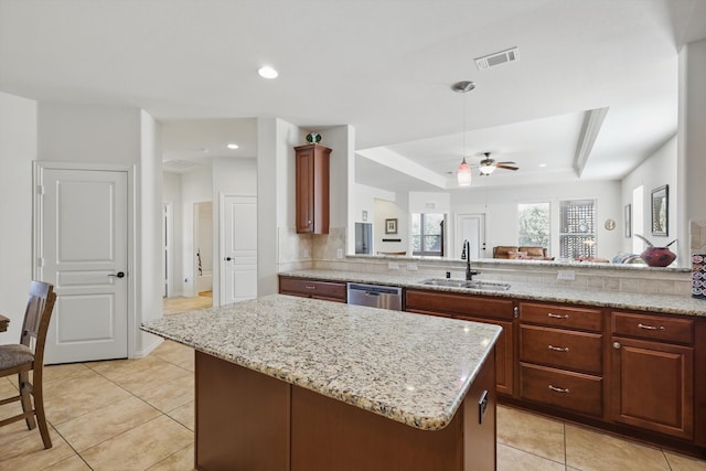 kitchen with visible vents, a sink, light stone counters, a kitchen island, and stainless steel dishwasher