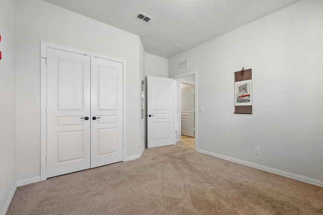 unfurnished bedroom featuring visible vents, baseboards, light colored carpet, and a closet