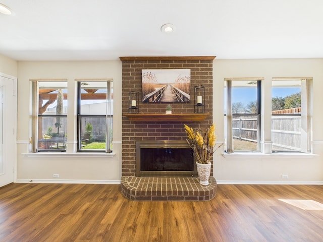 living area featuring a fireplace, wood finished floors, and baseboards