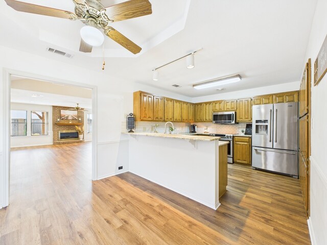 kitchen featuring visible vents, a sink, tasteful backsplash, appliances with stainless steel finishes, and light stone countertops