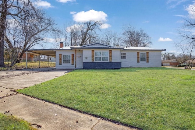 single story home with an attached carport, concrete driveway, a front lawn, and a chimney