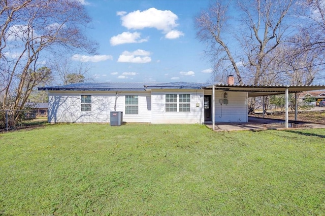 rear view of house featuring cooling unit, a chimney, metal roof, a yard, and a carport