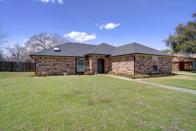 single story home with a front yard, fence, brick siding, and roof with shingles