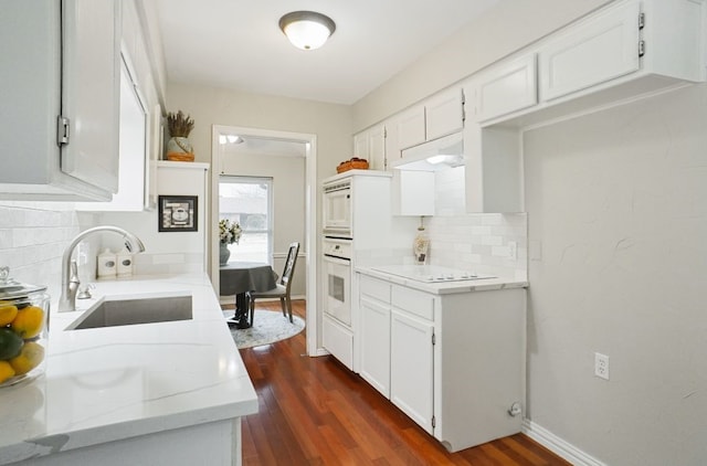 kitchen featuring tasteful backsplash, dark wood-type flooring, white appliances, white cabinetry, and a sink