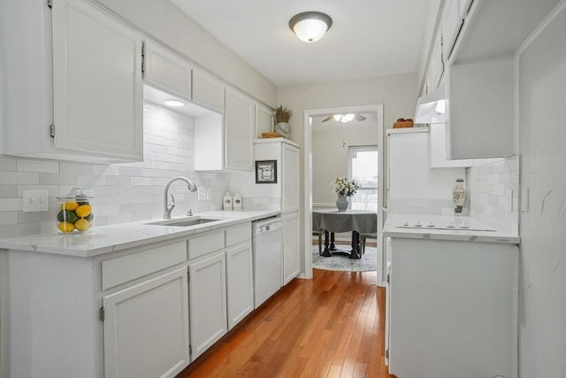 kitchen with a sink, hardwood / wood-style floors, white cabinets, and white dishwasher