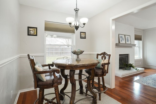 dining space with a wealth of natural light, a notable chandelier, and wood finished floors