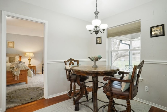 dining space with a notable chandelier, wood finished floors, and baseboards