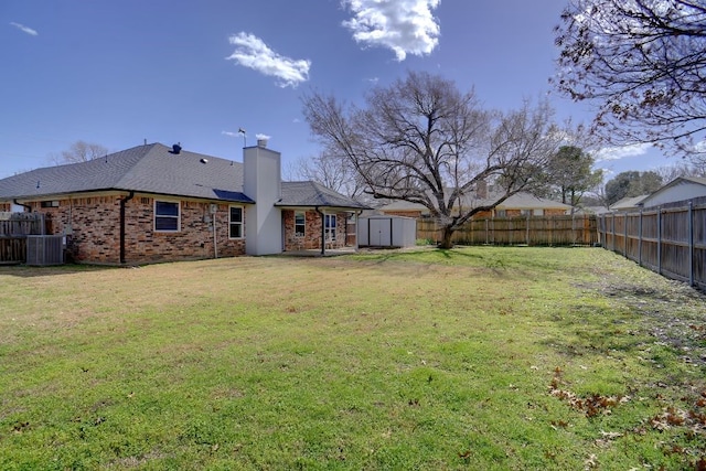 view of yard featuring an outbuilding, central AC unit, a fenced backyard, and a shed