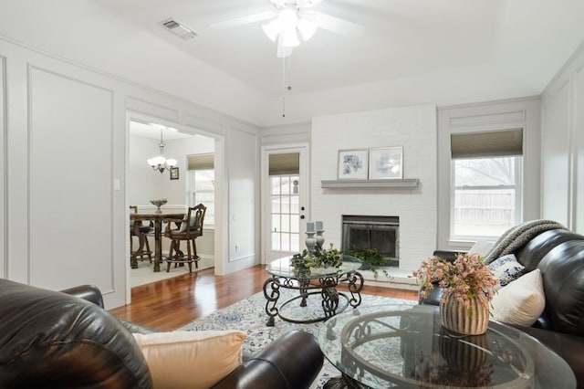 living room featuring visible vents, wood finished floors, a fireplace, and a decorative wall