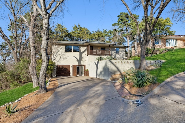 mid-century modern home with stucco siding, a balcony, concrete driveway, and a front yard