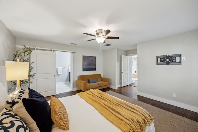 bedroom with a barn door, baseboards, visible vents, and wood finished floors