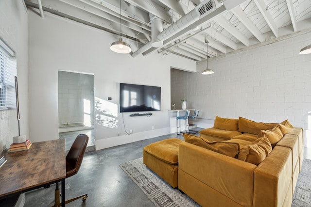 living area with beamed ceiling, finished concrete flooring, visible vents, and brick wall