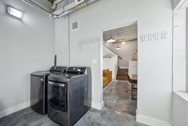 washroom featuring washing machine and clothes dryer, visible vents, laundry area, and baseboards