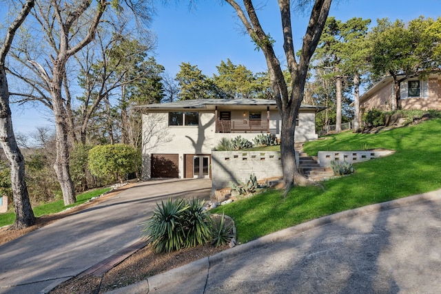 mid-century home with a garage, stucco siding, concrete driveway, and a front yard