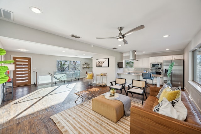 living area featuring visible vents, a healthy amount of sunlight, and wood finished floors