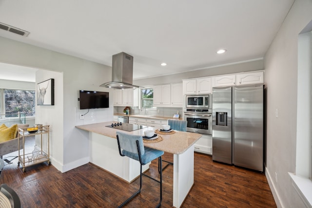 kitchen featuring island exhaust hood, a sink, white cabinetry, stainless steel appliances, and a peninsula