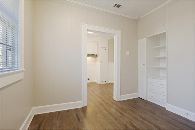 unfurnished bedroom featuring baseboards, visible vents, dark wood finished floors, ornamental molding, and a closet