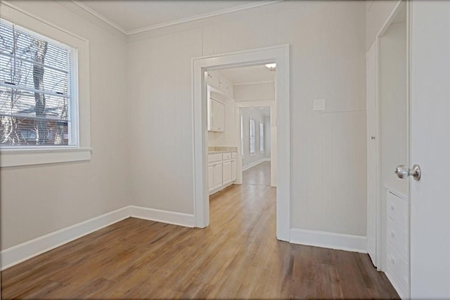 hallway featuring baseboards, light wood-style floors, and ornamental molding