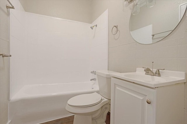 bathroom with vanity, wood finished floors, shower / washtub combination, tile walls, and toilet