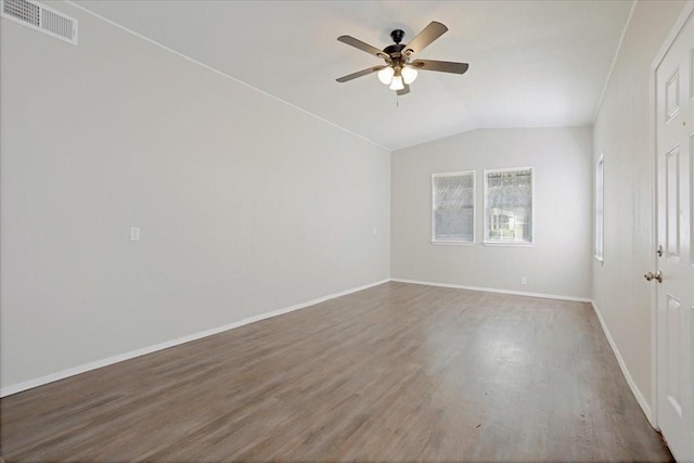 empty room featuring visible vents, a ceiling fan, wood finished floors, baseboards, and vaulted ceiling