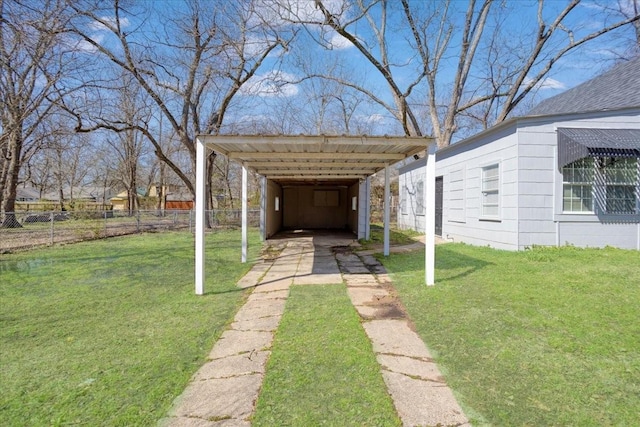 view of yard with a detached carport, driveway, and fence