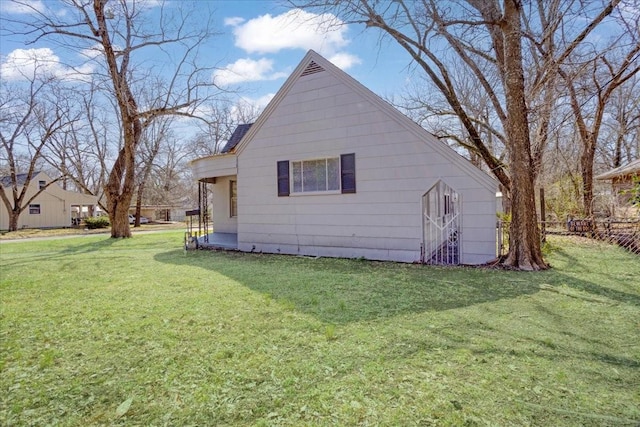 view of side of home featuring a lawn and fence