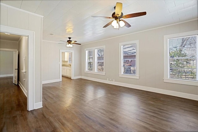 unfurnished room featuring baseboards, ornamental molding, dark wood-style floors, a decorative wall, and a ceiling fan