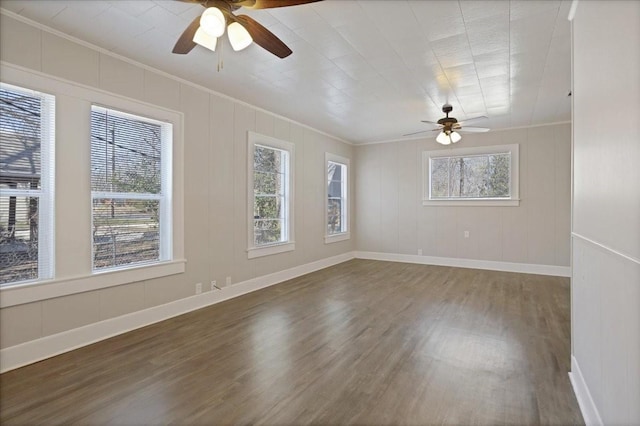 spare room with plenty of natural light, wood finished floors, a ceiling fan, and ornamental molding