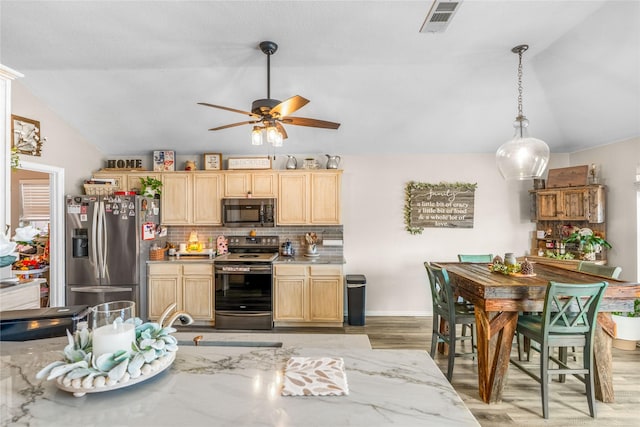 kitchen featuring ceiling fan, light brown cabinetry, vaulted ceiling, stainless steel appliances, and tasteful backsplash