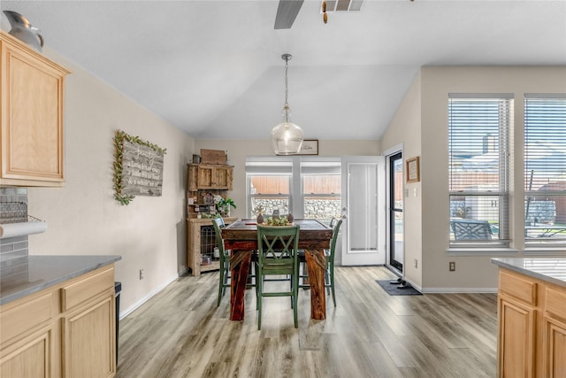 dining space featuring visible vents, light wood-style flooring, a ceiling fan, baseboards, and vaulted ceiling