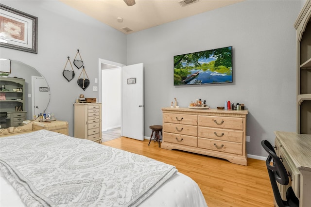 bedroom featuring ceiling fan, light wood-style floors, visible vents, and baseboards