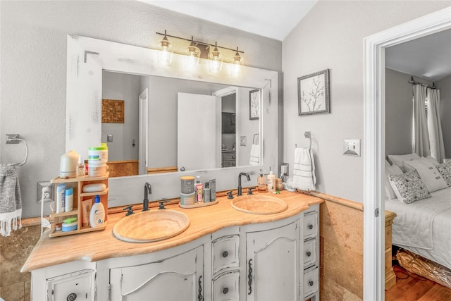 bathroom featuring double vanity, connected bathroom, wood finished floors, and a sink