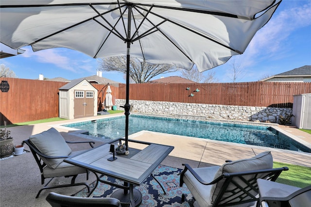 view of swimming pool with an outbuilding, a fenced in pool, a storage shed, and a fenced backyard