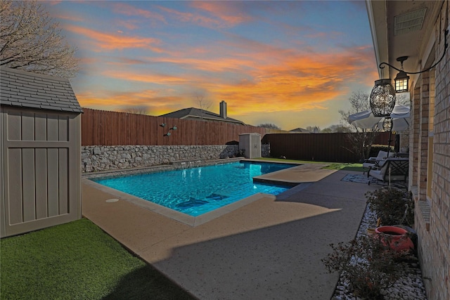 view of pool featuring a fenced in pool, a fenced backyard, an outdoor structure, a storage unit, and a patio area