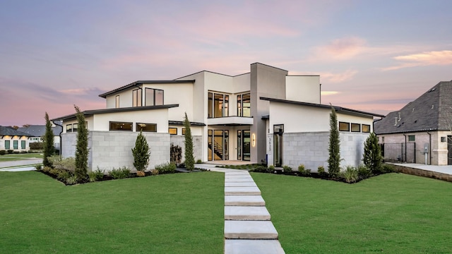 modern home featuring stucco siding, a front lawn, a garage, and stairs