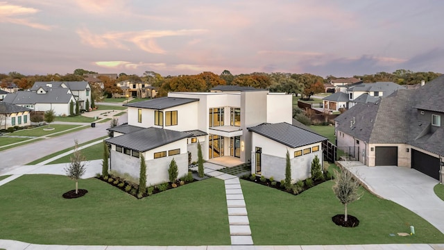 contemporary house featuring a yard, stucco siding, a garage, and a balcony