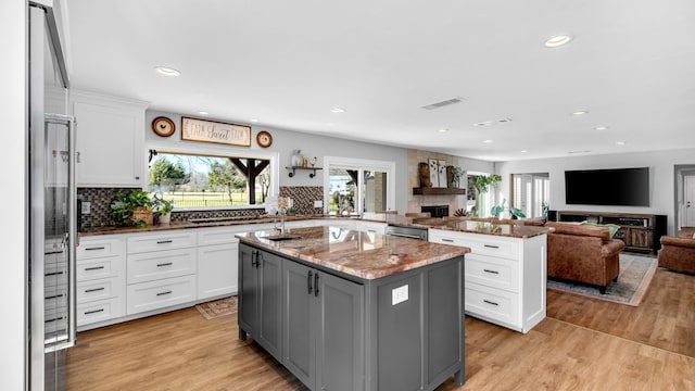 kitchen with a kitchen island, a fireplace, gray cabinets, white cabinetry, and light wood-type flooring