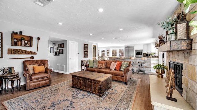 living area with light wood finished floors, visible vents, and recessed lighting