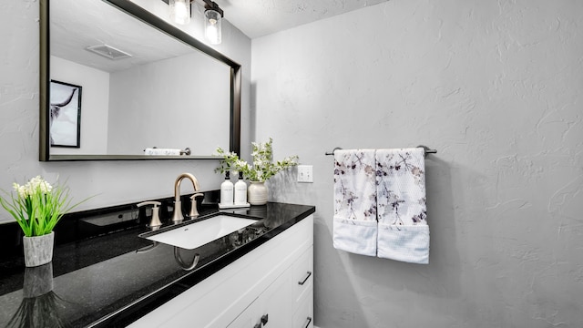 bathroom with vanity, a textured wall, and visible vents