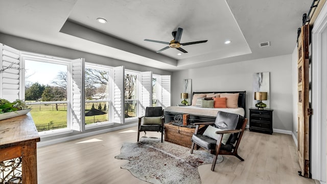 bedroom featuring visible vents, light wood-type flooring, and a tray ceiling