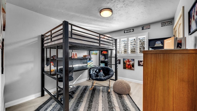 bedroom featuring wood finished floors, baseboards, and a textured ceiling