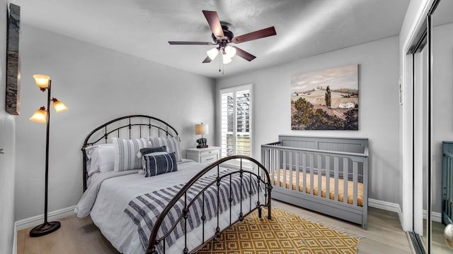 bedroom with a closet, baseboards, wood finished floors, and a ceiling fan