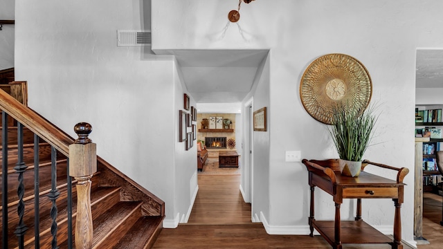 interior space with wood finished floors, visible vents, a warm lit fireplace, and baseboards