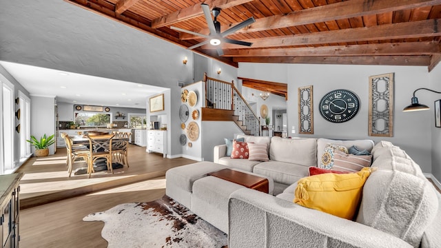 living room featuring baseboards, stairs, beam ceiling, wooden ceiling, and wood finished floors