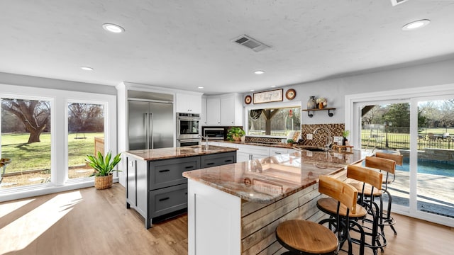 kitchen with visible vents, a sink, gray cabinetry, light wood-style floors, and appliances with stainless steel finishes