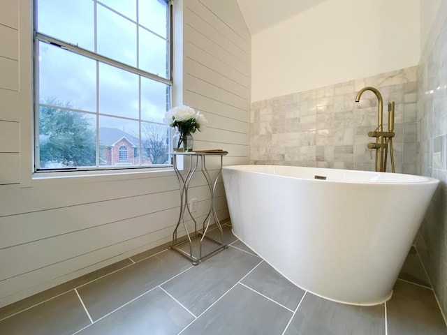 full bath featuring tile patterned floors, a soaking tub, and tile walls