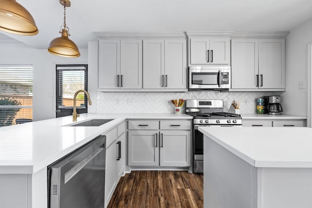 kitchen featuring a sink, stainless steel appliances, a peninsula, light countertops, and decorative backsplash