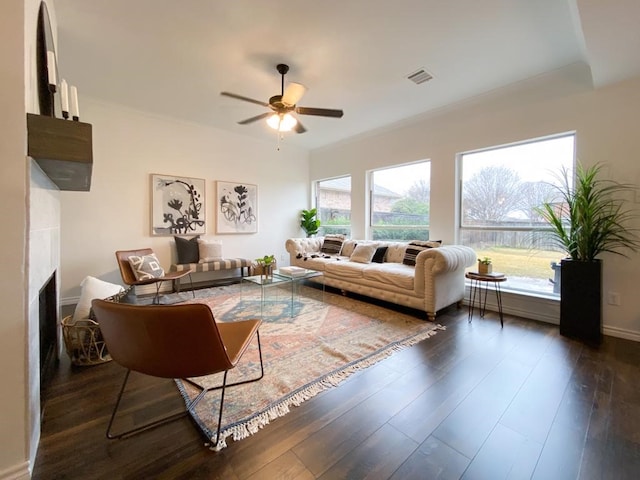 living area featuring dark wood finished floors, plenty of natural light, a fireplace, and ceiling fan